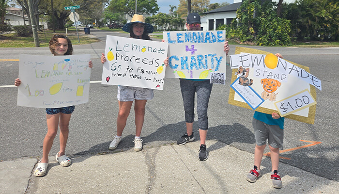 Kids and parents from Helping Hands Happy Hearts Tampa holding up Lemonade 4 Charity Signs for Frankie's Friends fundraiser